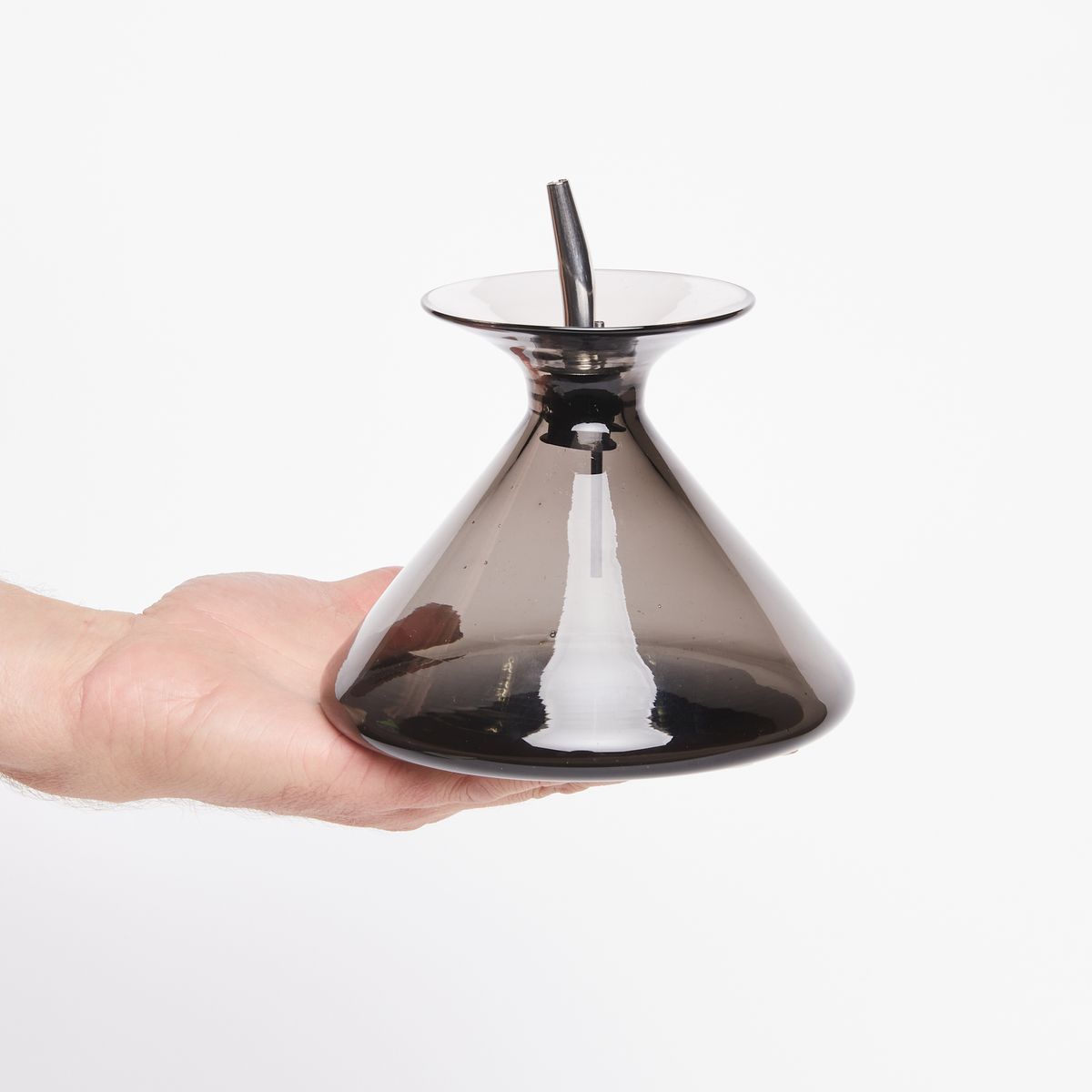 Hand holding a dark grey clear glass cone with pour spout on top
