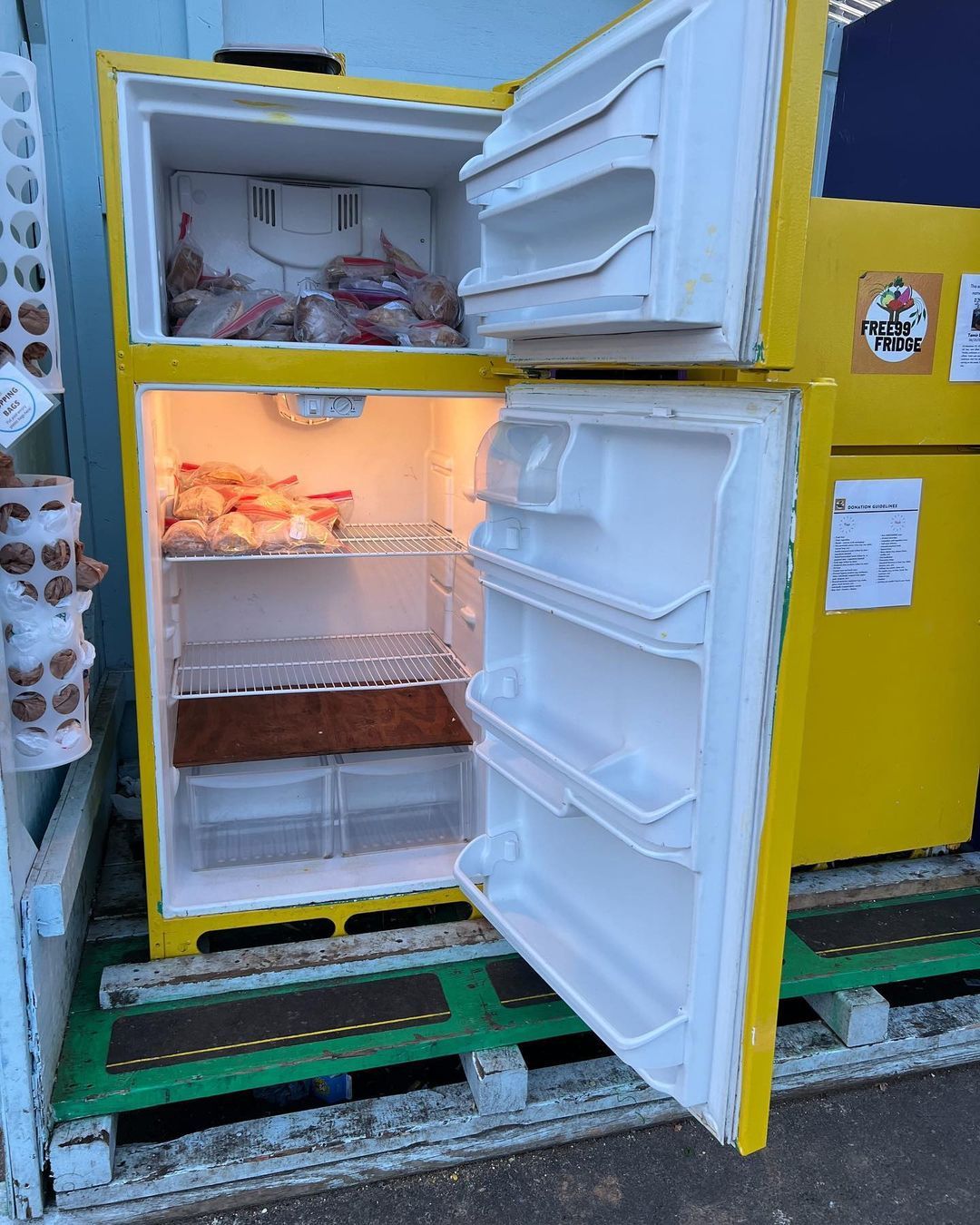 A bright yellow fridge with its doors open, revealing some food. These fridges are filled with free food throughout Atlanta.