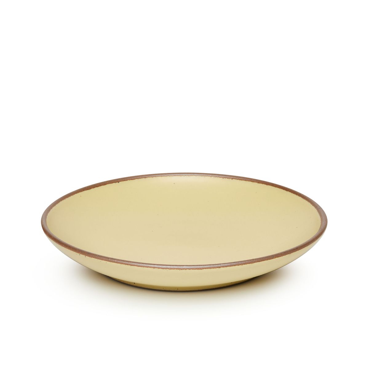 A large ceramic plate with a curved bowl edge in a light butter yellow color featuring iron speckles and an unglazed rim