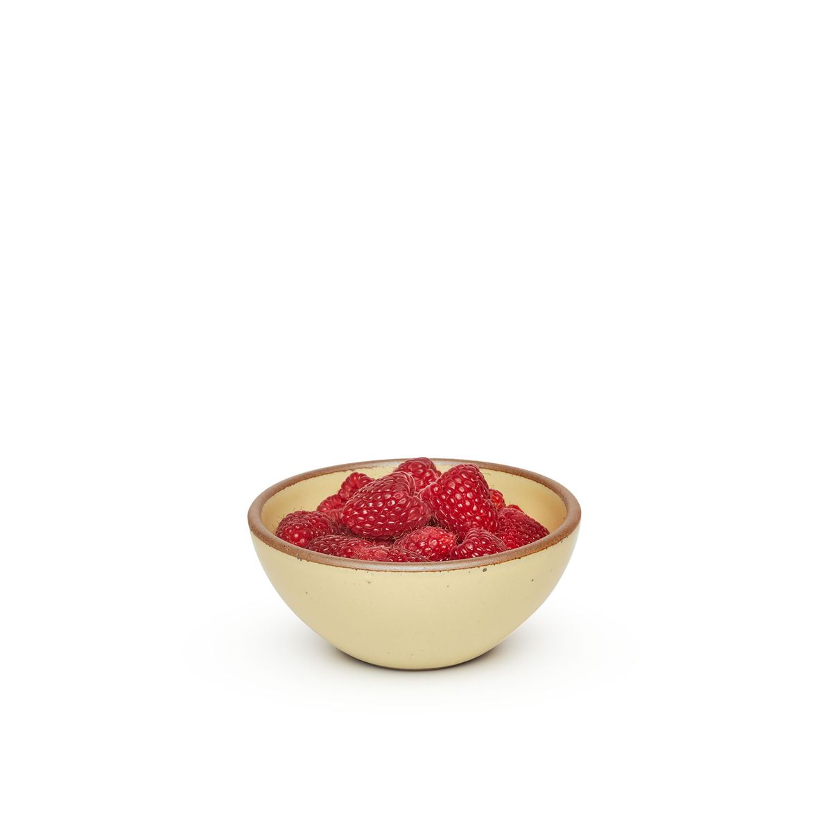 A small dessert sized rounded ceramic bowl in a light butter yellow color featuring iron speckles and an unglazed rim, filled with strawberries