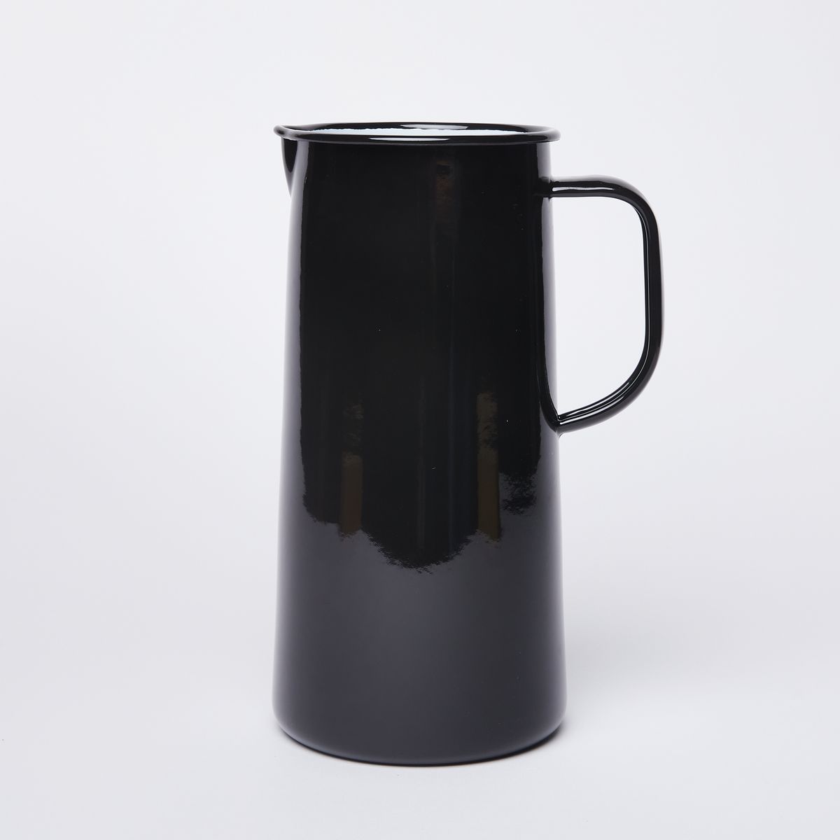 Shiny black cylindrical jug, with white interior, a spout on the left, and a handle on the right
