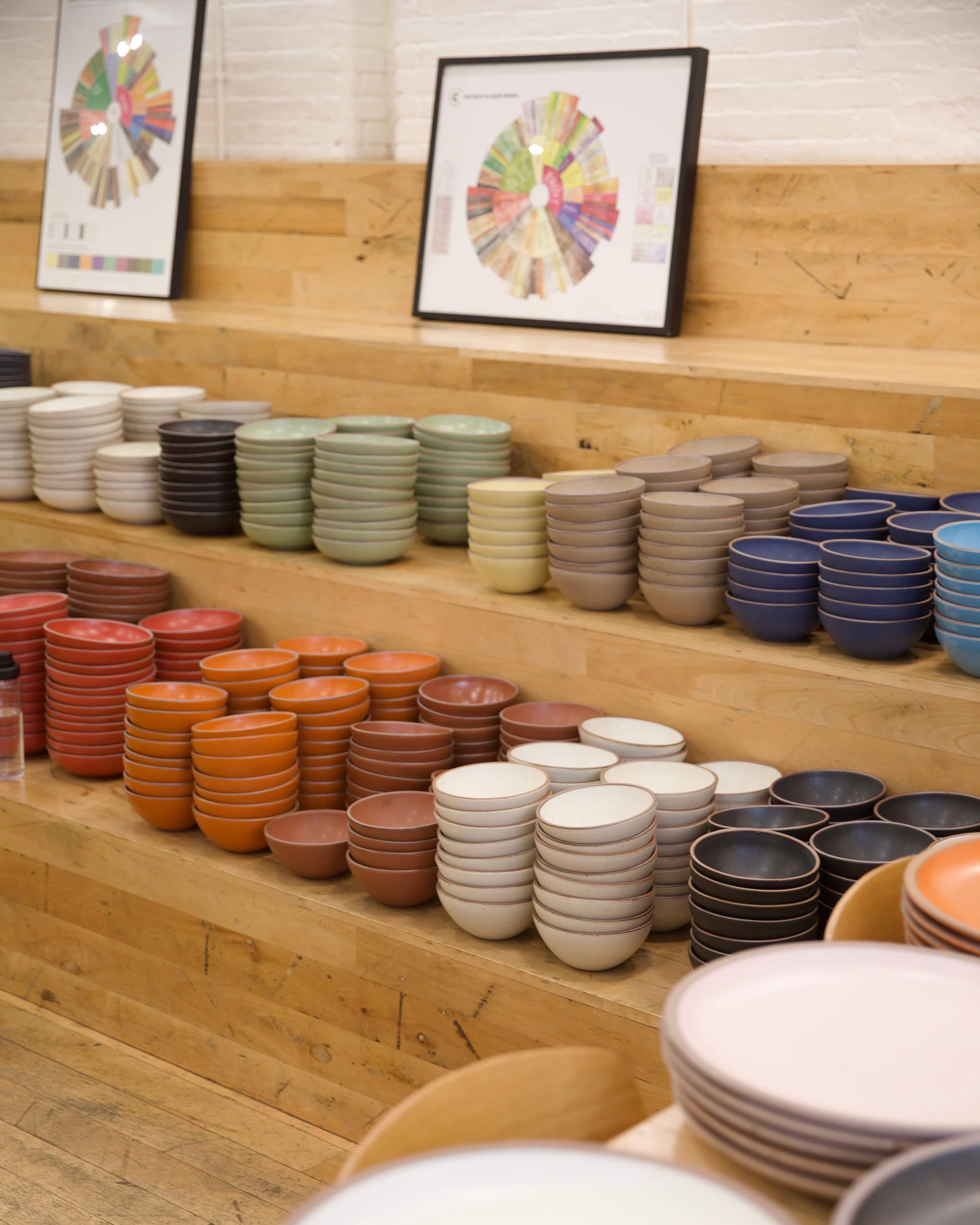 On wooden steps, there are large tall stacks of ceramic bowls in all different colors of the rainbow