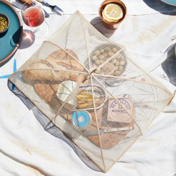 Linen dinner cover over bread, olives and tinned fish