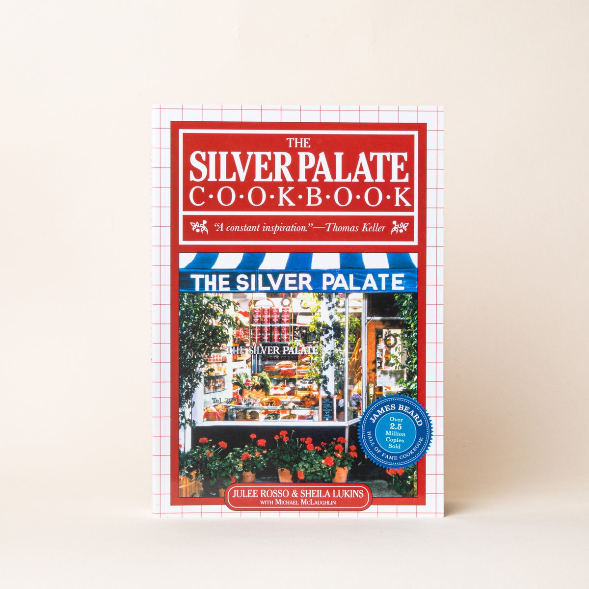 A book with a red cover and a photo of a storefront and outside garden, the title reads "The Silver Palate Cookbook"