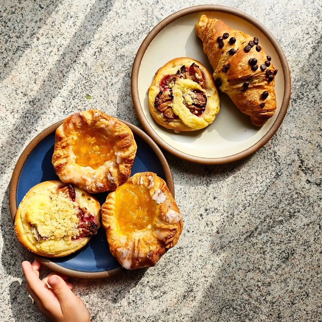 2 Medium ceramic plates in blue and off-white colors, with pastries in daylight.