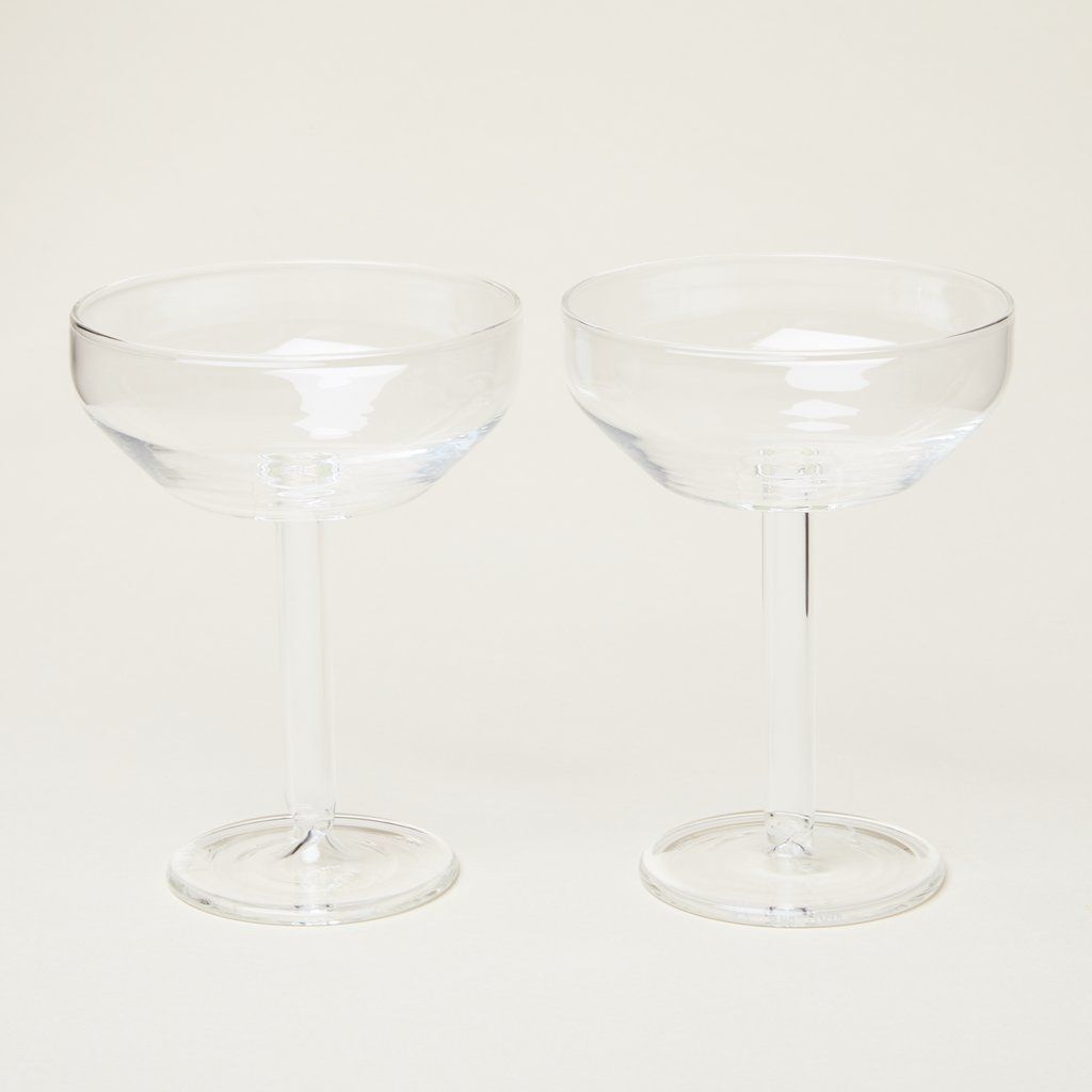Two clear glass Martini coupes on an off-white background
