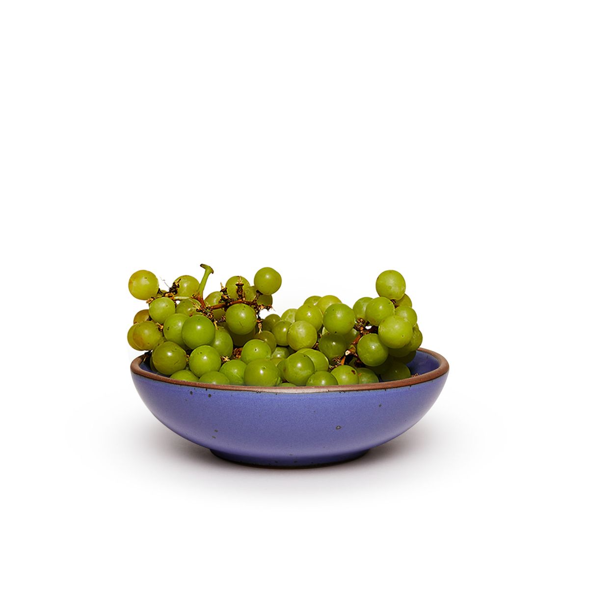 Green grapes in a dinner-sized shallow ceramic bowl in a true cool blue color featuring iron speckles and an unglazed rim