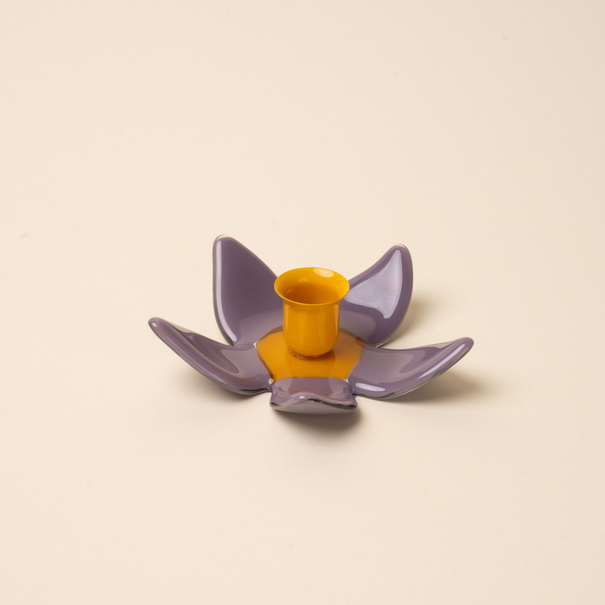 A sculptural glass purple flower candleholder with an orange center.