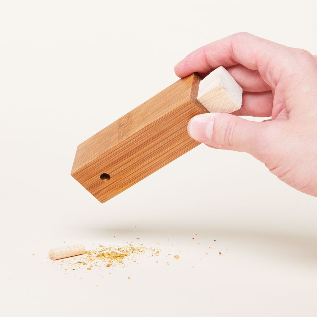 Spice on the table rectangular spice dispenser with a peg sticking out of one side and a wood stopper, held in a hand