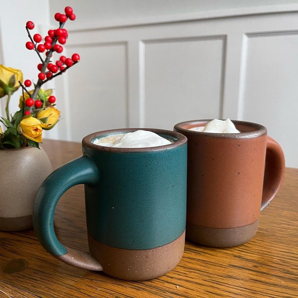 Two East Fork Mugs, with the top of the foamy latte peaking over their brims.