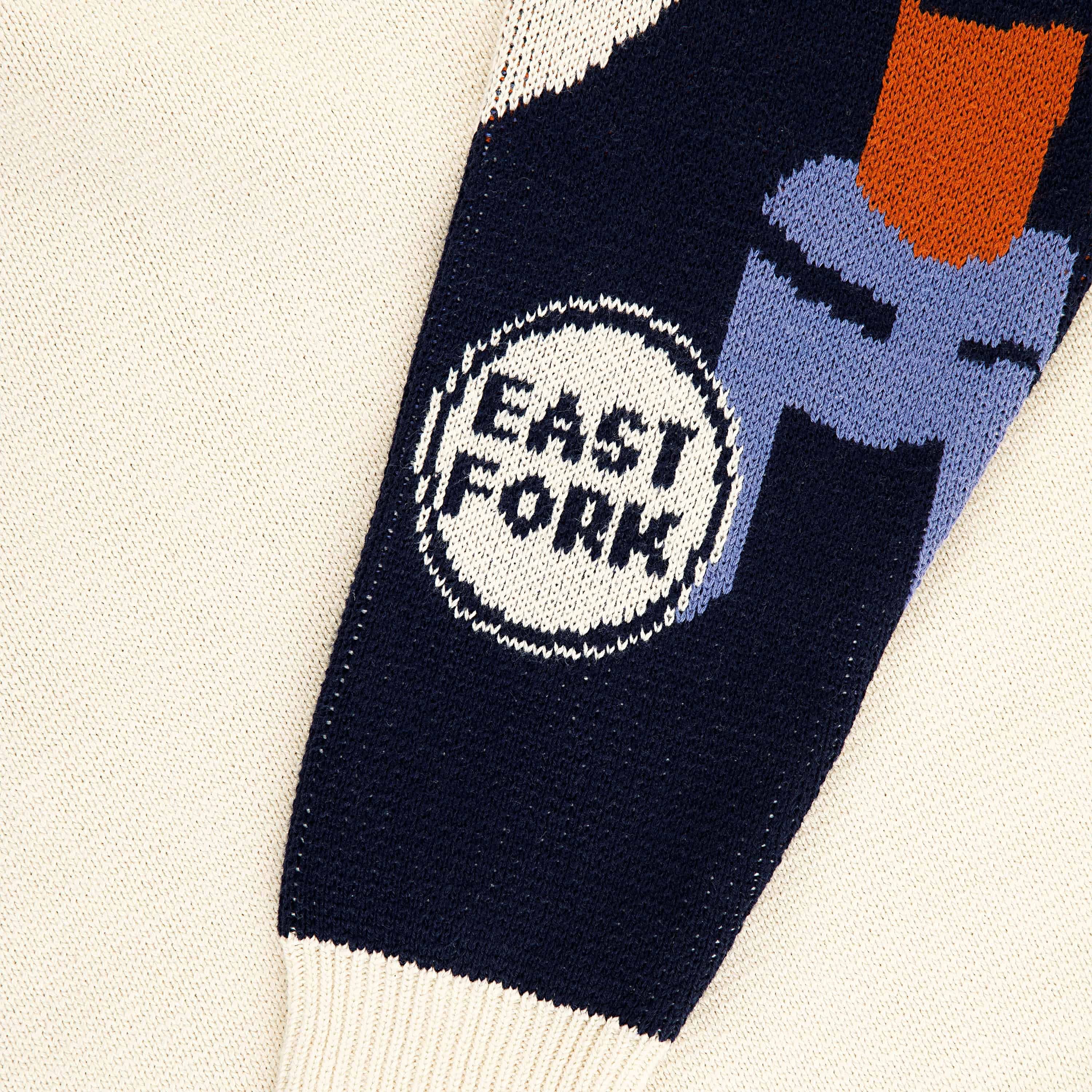 A close up of a workshop sleeve with a circle with text that reads "East Fork" with navy, terracotta, blue, and cream colors.