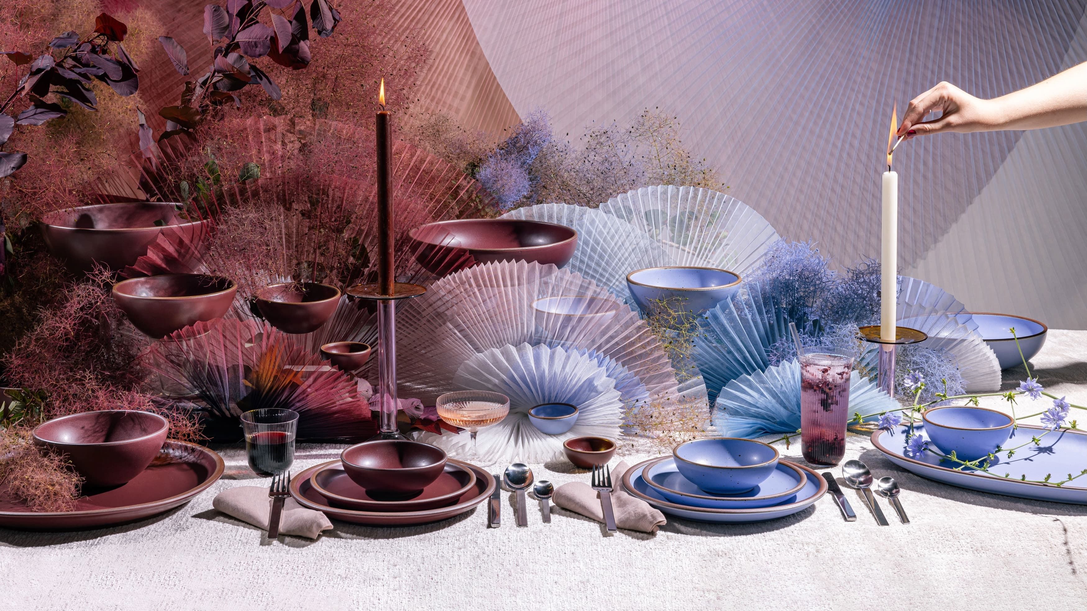 A beautiful tablescape filled with artful fabric sculptures, and ceramic plates and bowls in periwinkle and plum colors