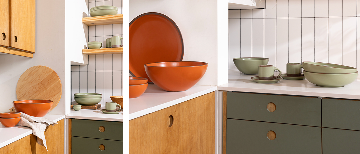 Two photos featuring a corner of a kitchen. On the counters are bold orange and sage green ceramic bowls, a waffle weave kitchen towel, and a round wooden serving board. The kitchen cabinets are warm wood and muted green colors against a vertical white subway tile backsplash.