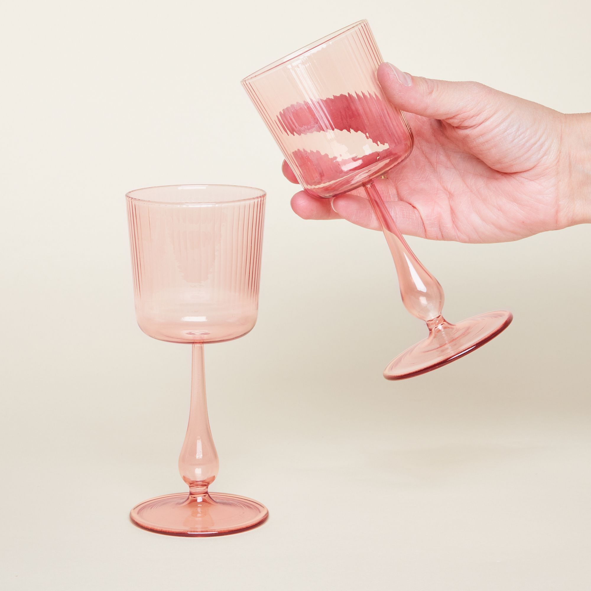 Stemmed wine glasses with grooves on the cup and stems that bow out at the end before their foot. They come in three colors: pale yellow, pale green and pale pink.