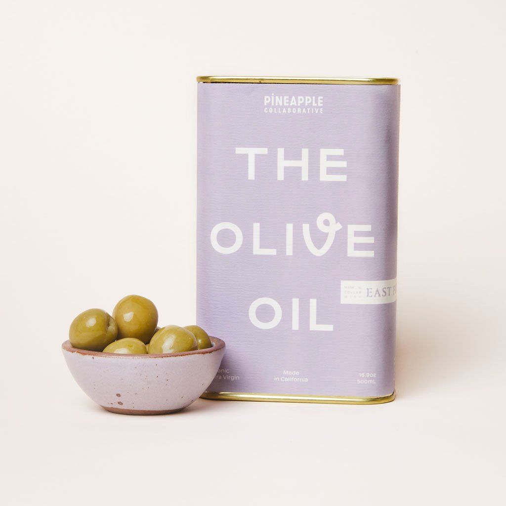 A purple can of olive oil with an East Fork Bitty Bowl in Taro filled with green olives