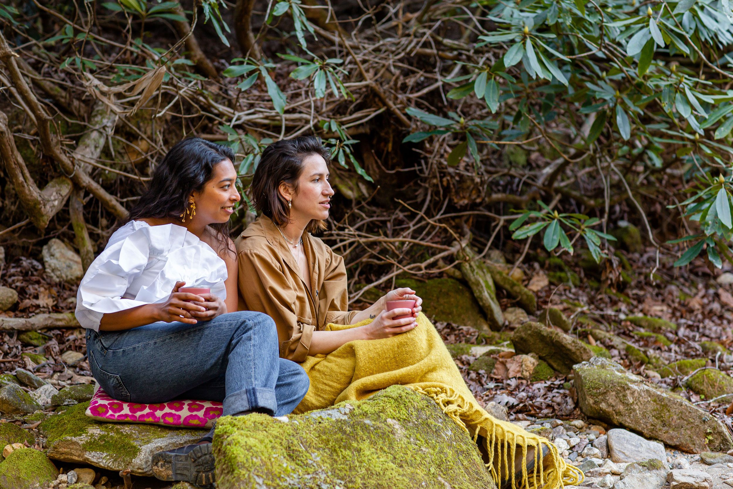 Sana Jeveri Kadri and Connie Matisse, two fierce female CEOs, sip chai and stay warm under blankets along the Hungry River, a short walk through the wood's from Connie's house in Flat Rock.