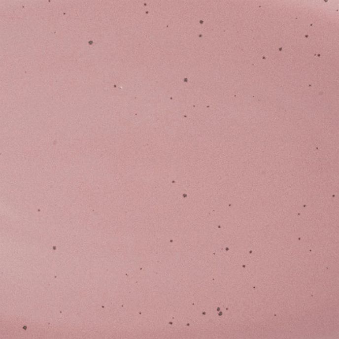 A closeup of a ceramic plate in a soft rosey pink color with iron speckles throughout