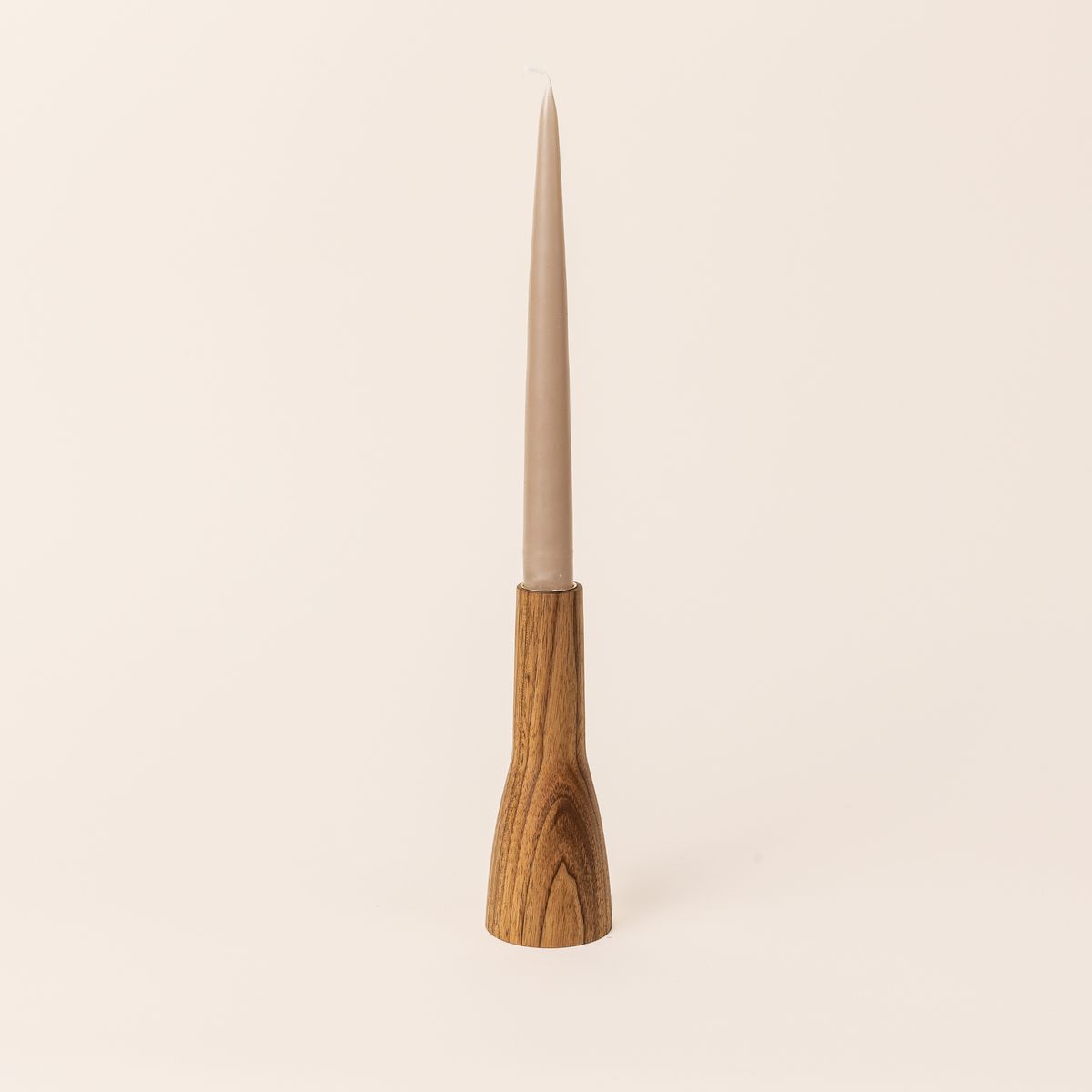 A butternut wood candle holder that is narrow shaped with a wider base on the bottom half and a thinner cylinder on the top half. A taper candle sits on the top.