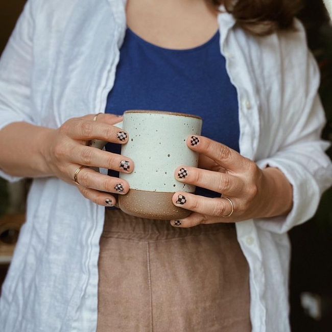 A woman with fashionable nail art clothes an East Fork Mug in Panna Cotta. It matches her drapey, neutral-colored linen outfit.