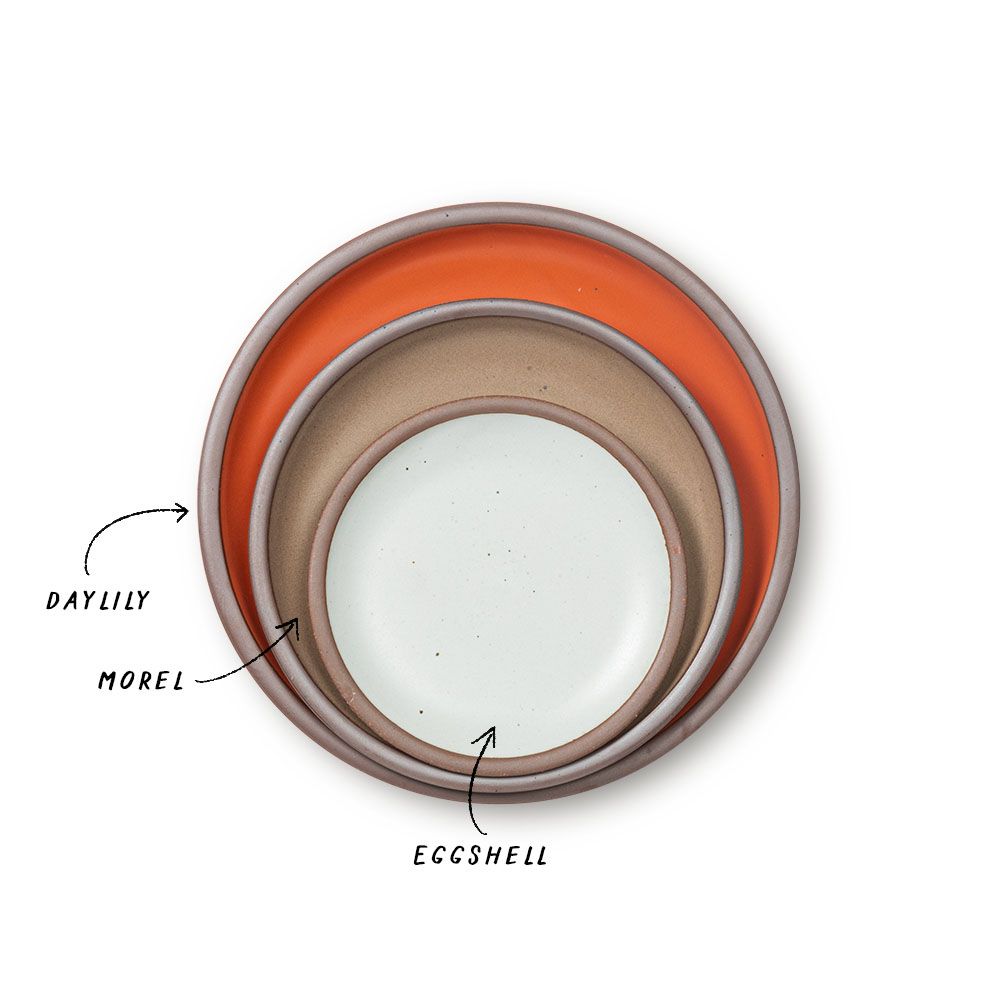 A stack of ceramic plates in a bold orange, muted tan, and cool white colors.