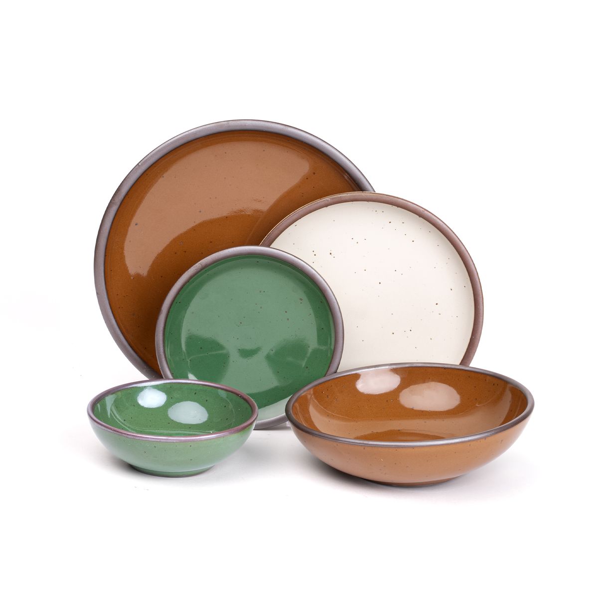 A dinner plate and everyday bowl in glossy caramel brown, a breakfast bowl and a cake plate in glossy emerald green and a side plate in a white cream color paired together featuring iron speckles