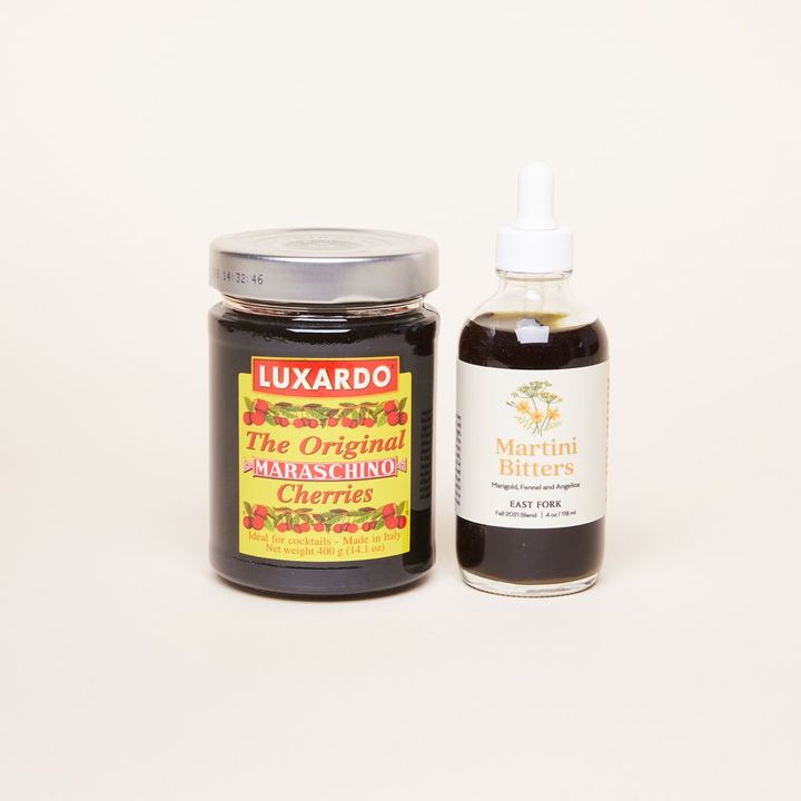 Jar of luxurous cocktail cherries next to dropper bottle of martini bitters