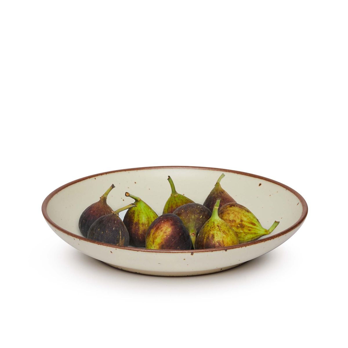 Figs on a large ceramic plate with a curved bowl edge in a warm, tan-toned, off-white color featuring iron speckles and an unglazed rim.