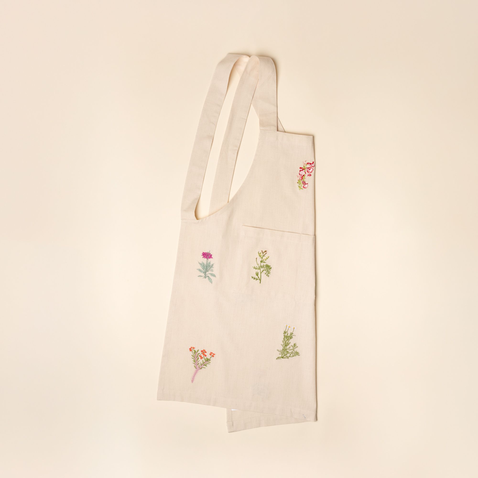A folded canvas apron with embroidered flowers on it.