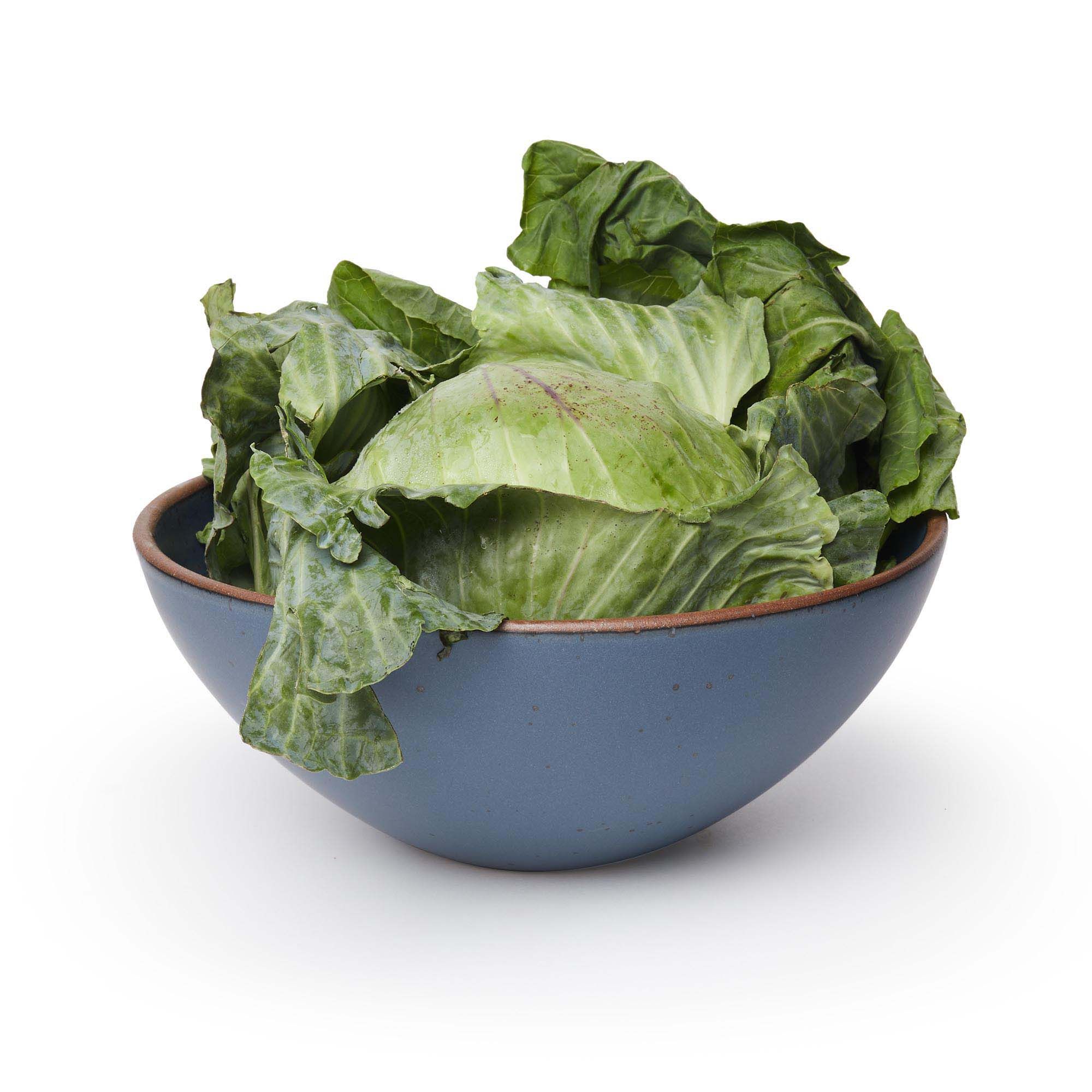 A large ceramic mixing bowl in a toned-down navy color featuring iron speckles and an unglazed rim, filled with lettuce