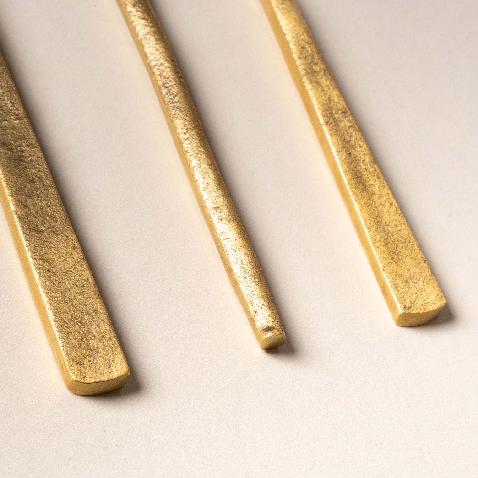 Close up of the handles of brass flatware utensils arranged on a light background