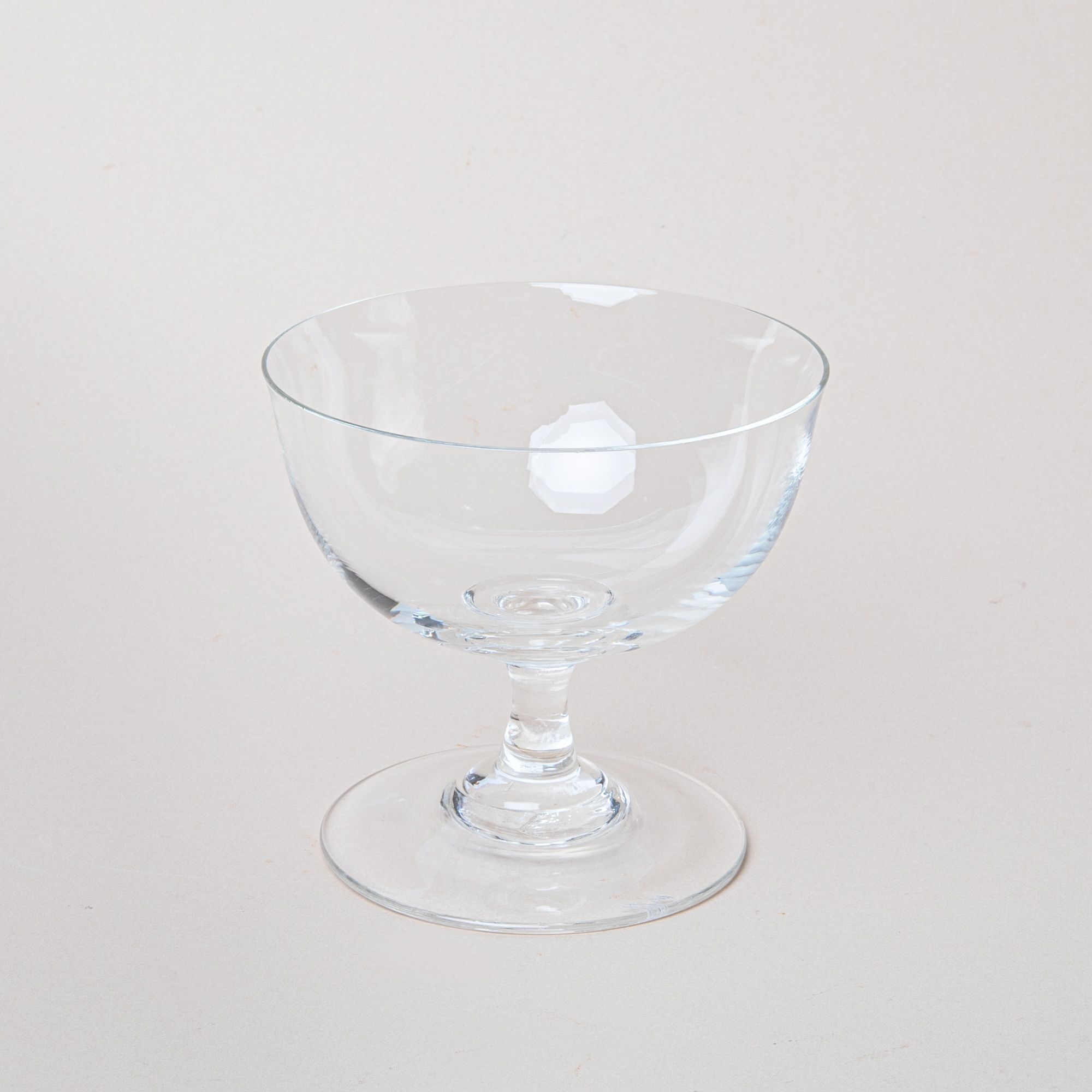 A clear coupe glass with a short stem and wide base