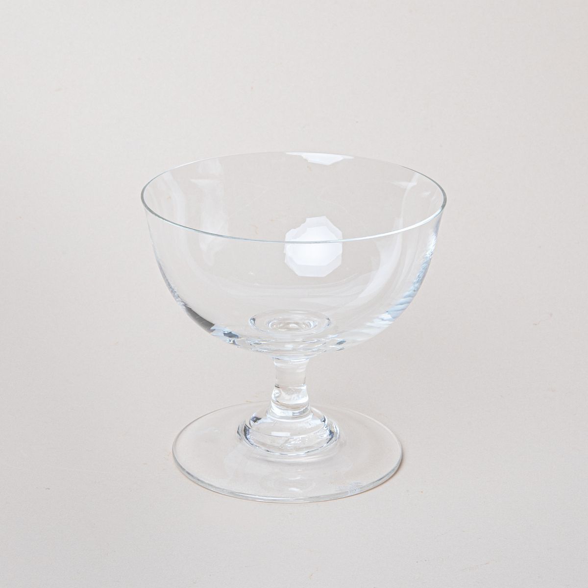A clear coupe glass with a short stem and wide base