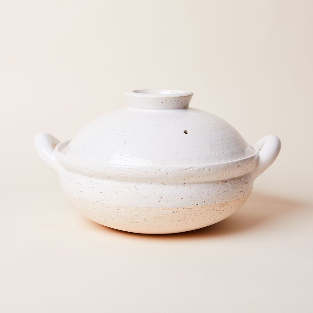 A white clay pot steamer with handles and lid