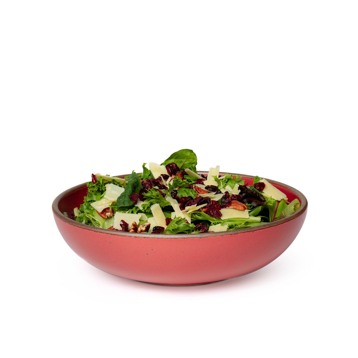 A large shallow serving ceramic bowl in a bold red color featuring iron speckles and an unglazed rim, filled with salad.