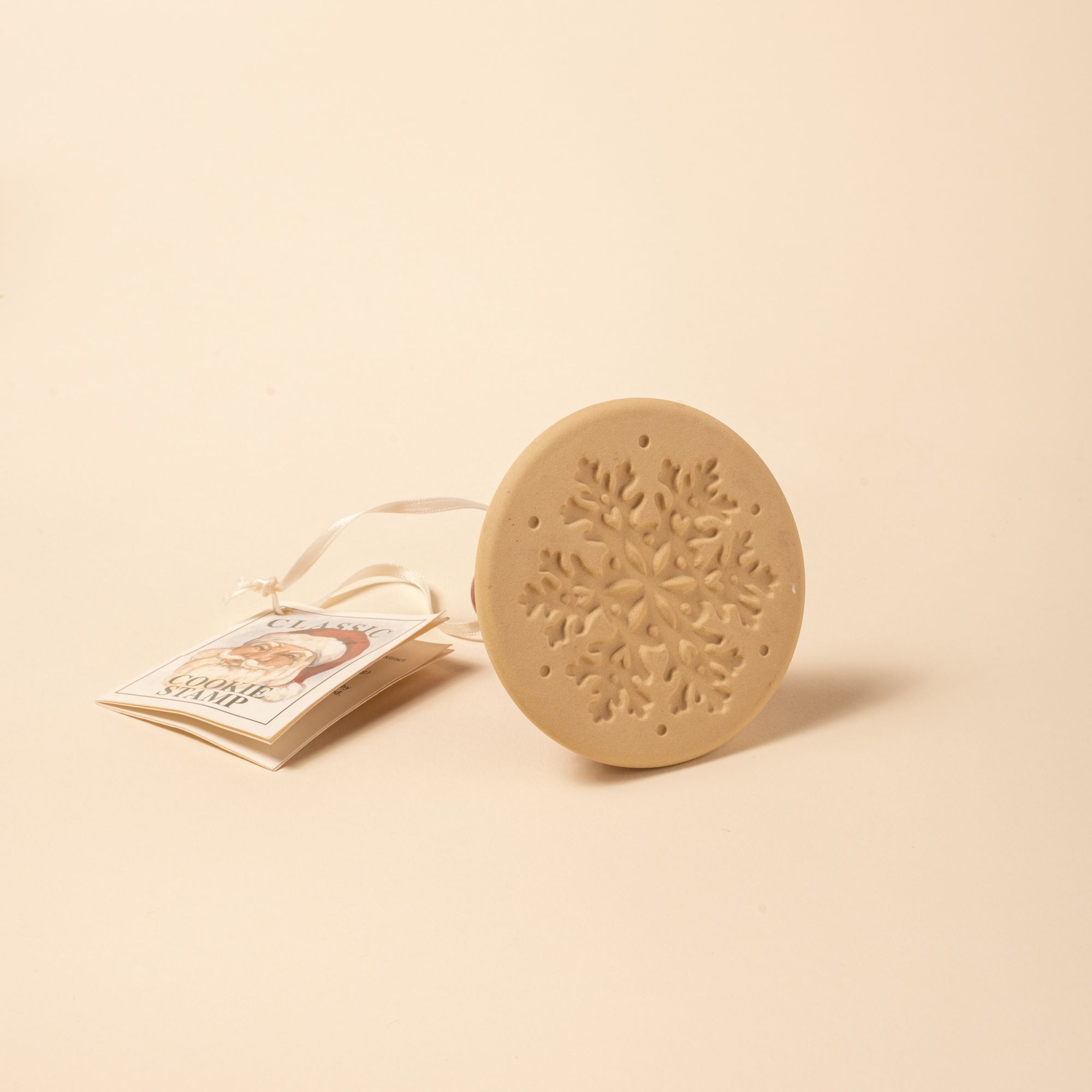 A round cookie stamp with a snowflake design, attached to a ribbon and tag labeled “Classic Cookie Stamp.”