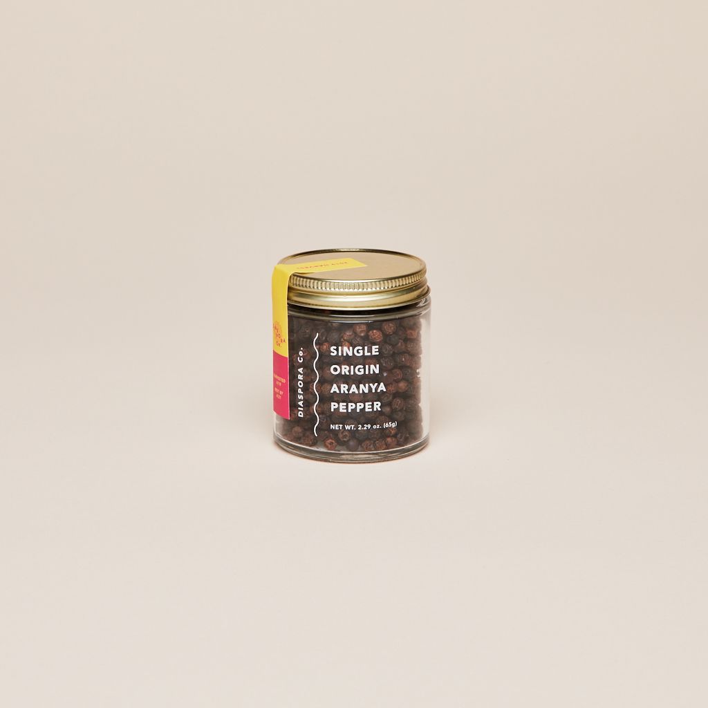 Glass jar with gold lid filled with whole peppercorns