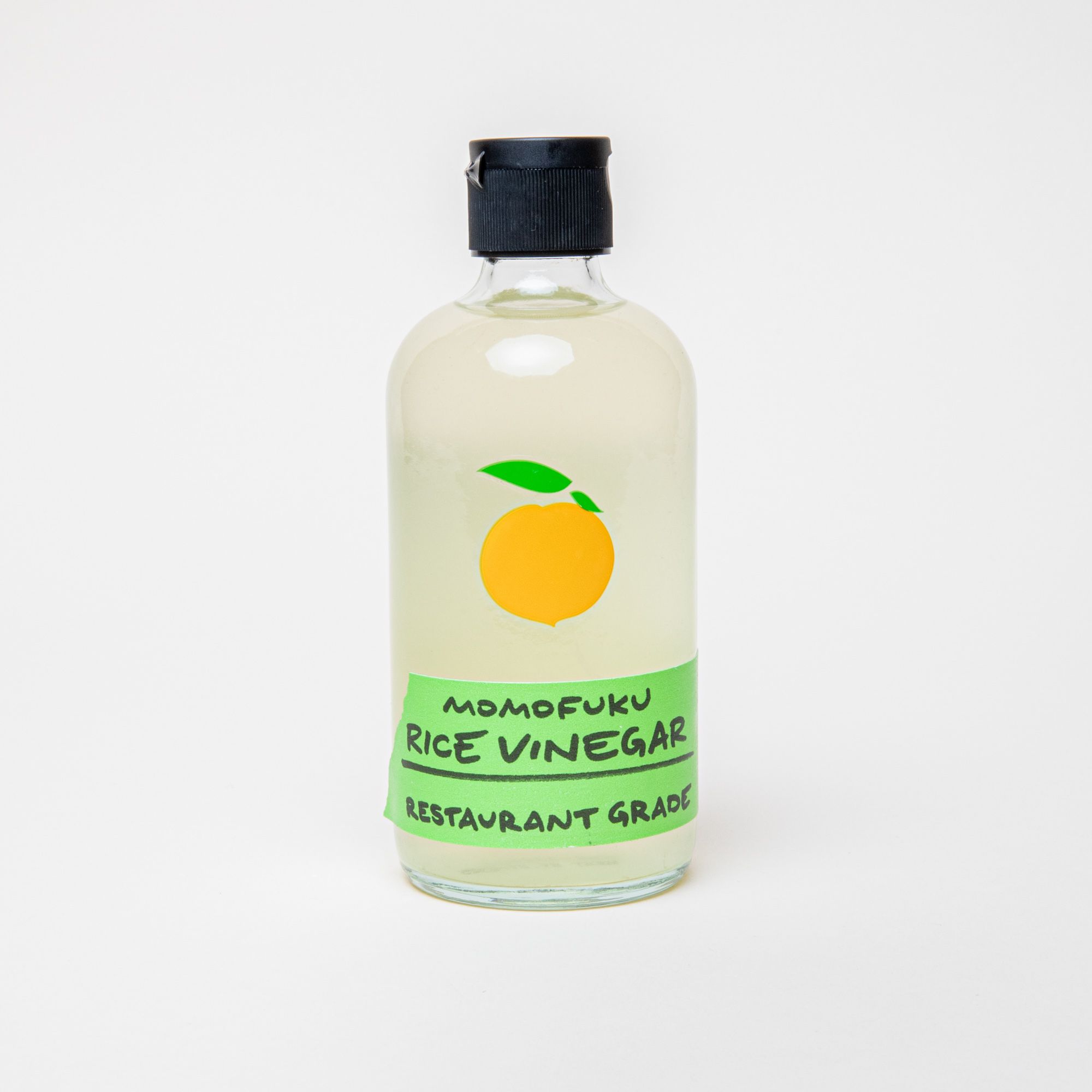 A clear bottle with a black top filled with vinegar and a label that reads 'Momofuku Rice Vinegar"