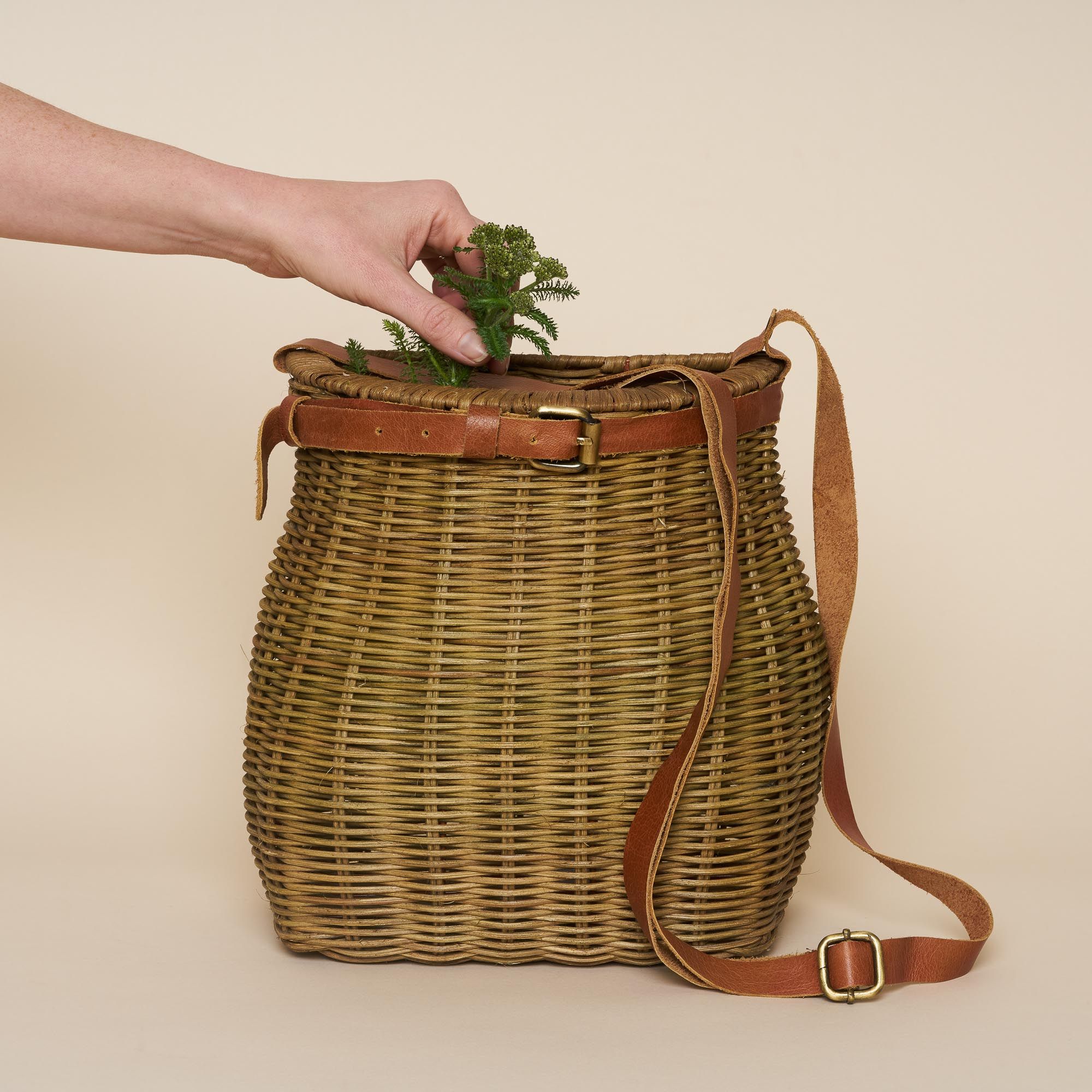 A wicker foraging basket with a leather strap