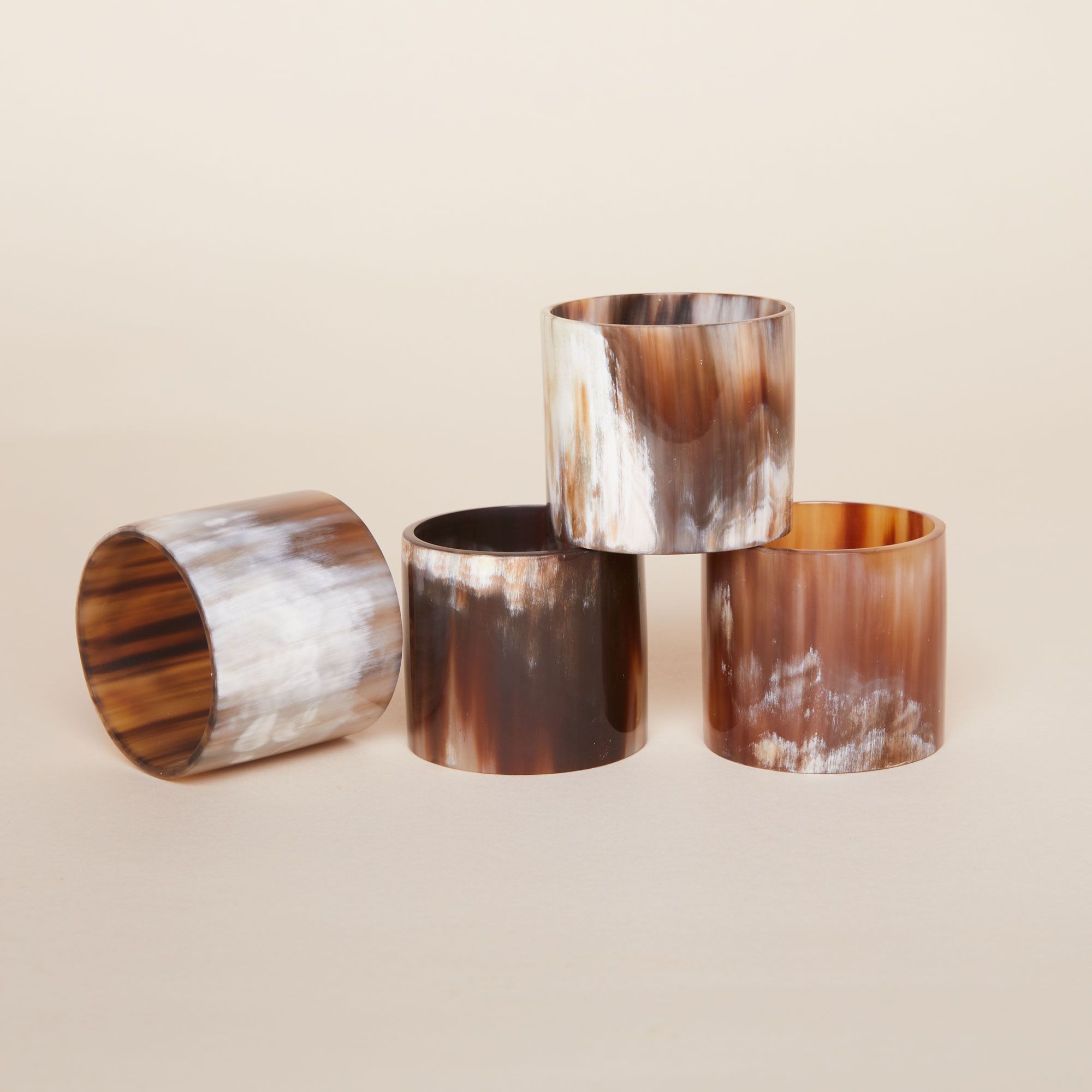 Four cylindrical napkin rings in shades of white, gray and brown