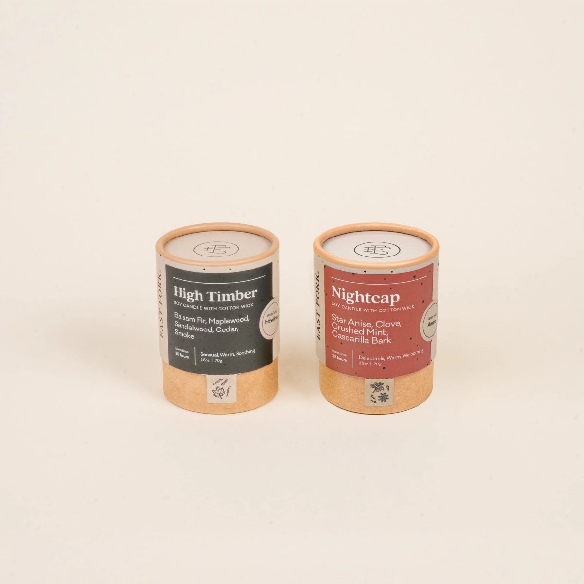 Two small cardboard packaging tubes with a candle inside each with branding on the outside that says 'High Timber' and 'Nightcap'