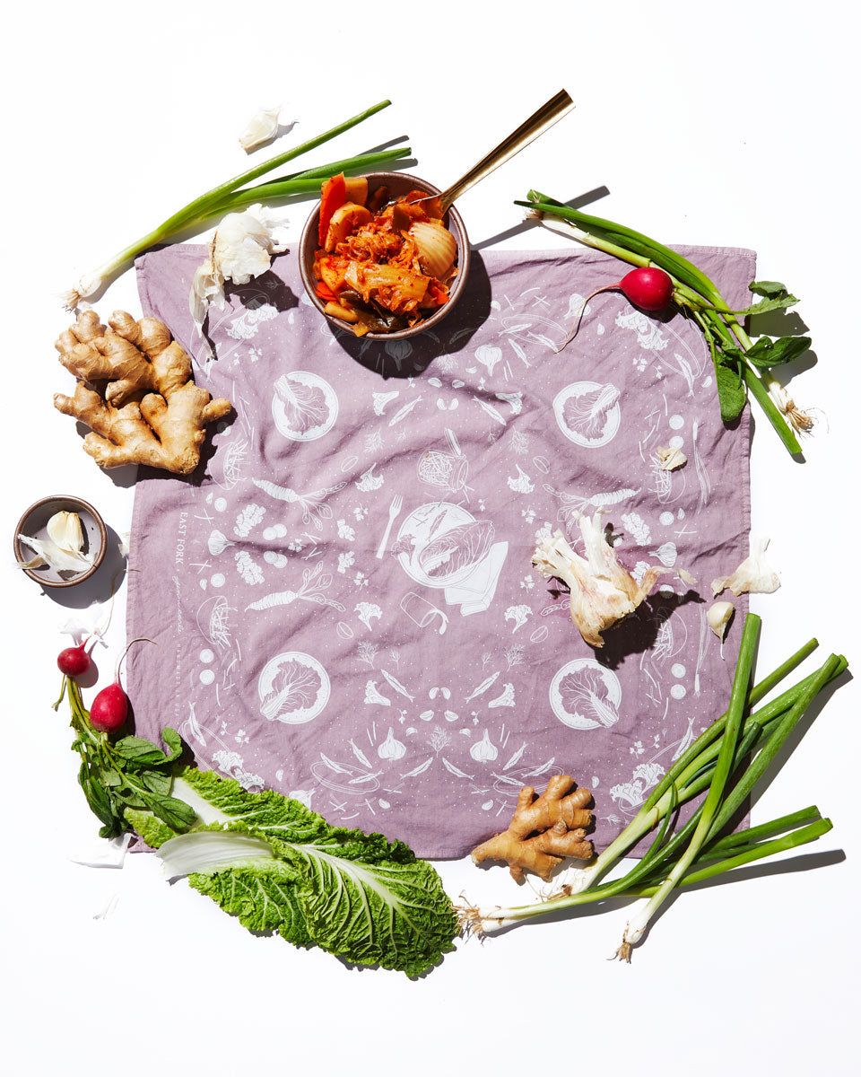 An artful flatlay of a lavender bandana surrounded by whole ginger, radishes, green onions and small bowls