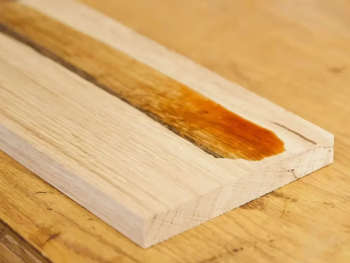 A piece of wood being stained with some kind of liquid to make the color darker