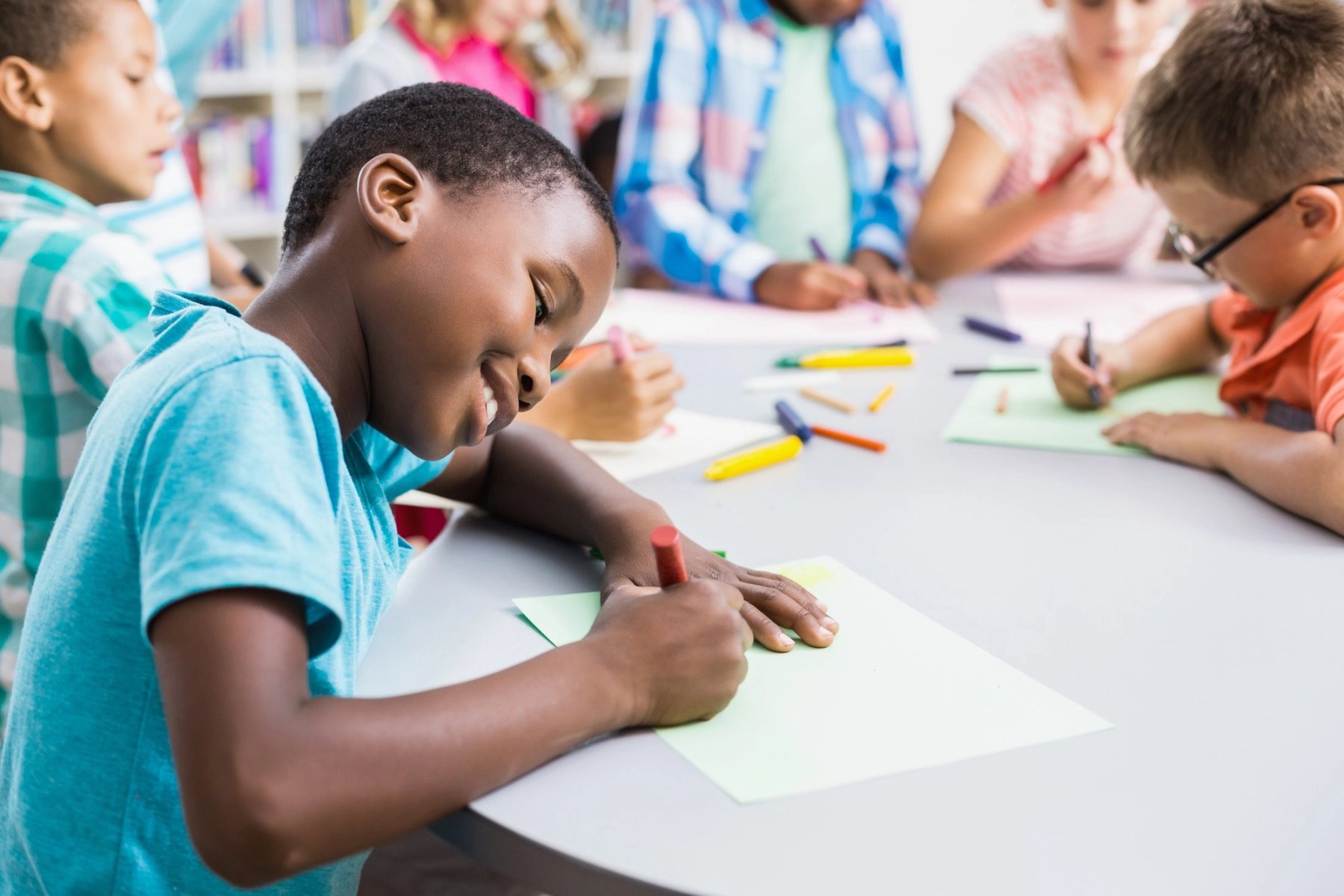 Grupo diverso de niñas y niños dibujando juntos en una mesa de trabajo.