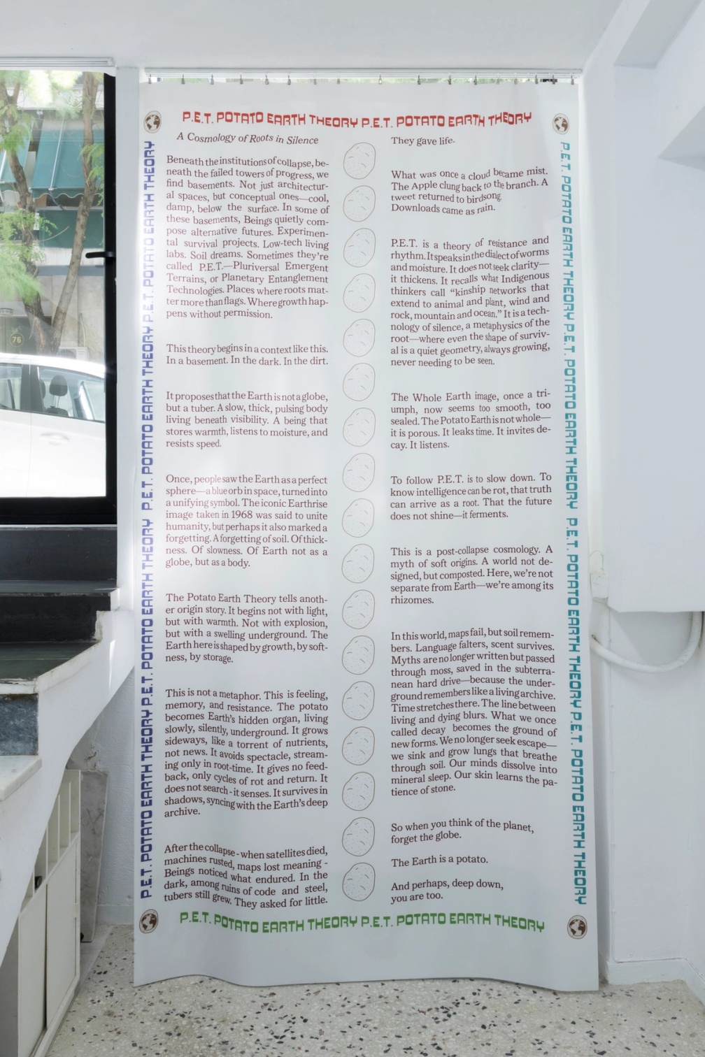 Slide 1/5: Angelo Plessas, Potato Earth Theory (P.E.T.): A Cosmology of Roots in Silence, 2025, text on fabric, 300 x 160 cm. Photo by Nefeli Papaioannou.