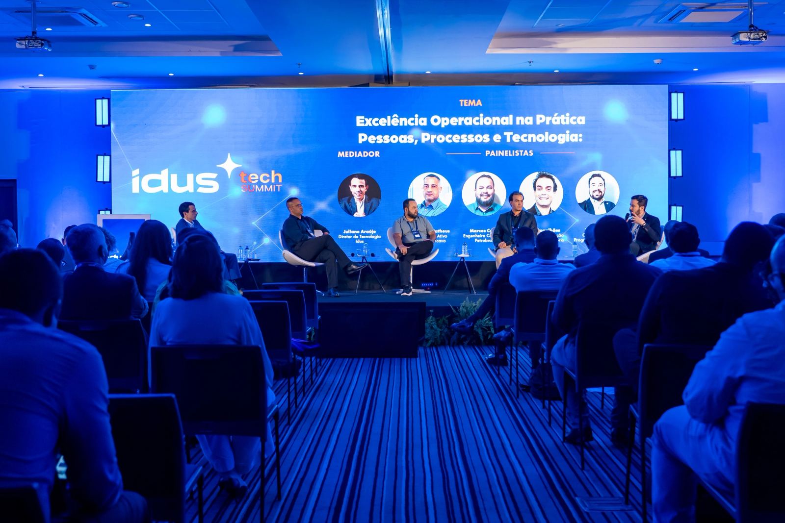 Encontro executivo em sala moderna com paredes azul-marinho e apresentação em tela