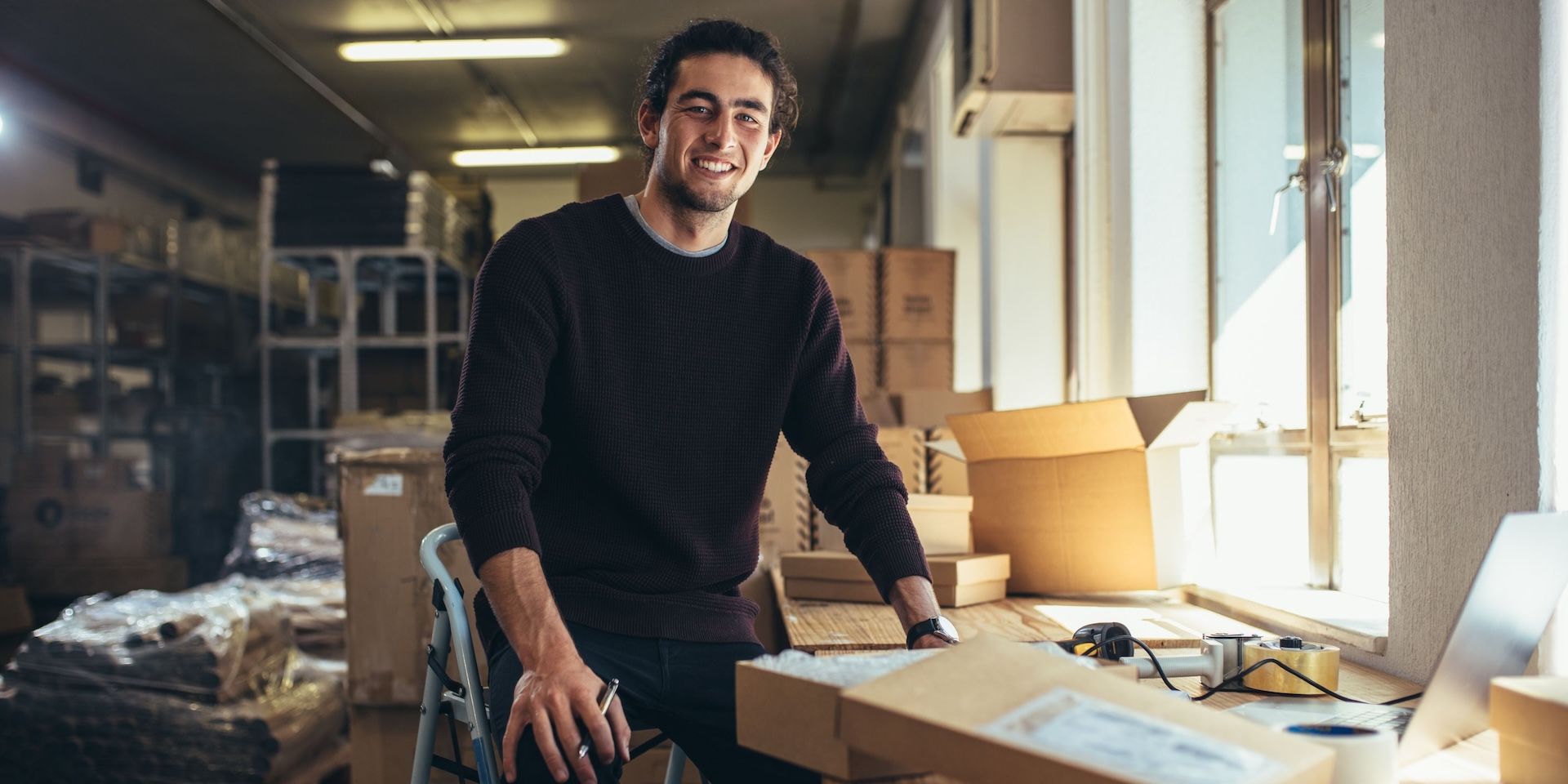small business owner doing accounting on computer in his warehouse