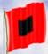 An image of a red flag with a black square in the center of it blowing in the wind.