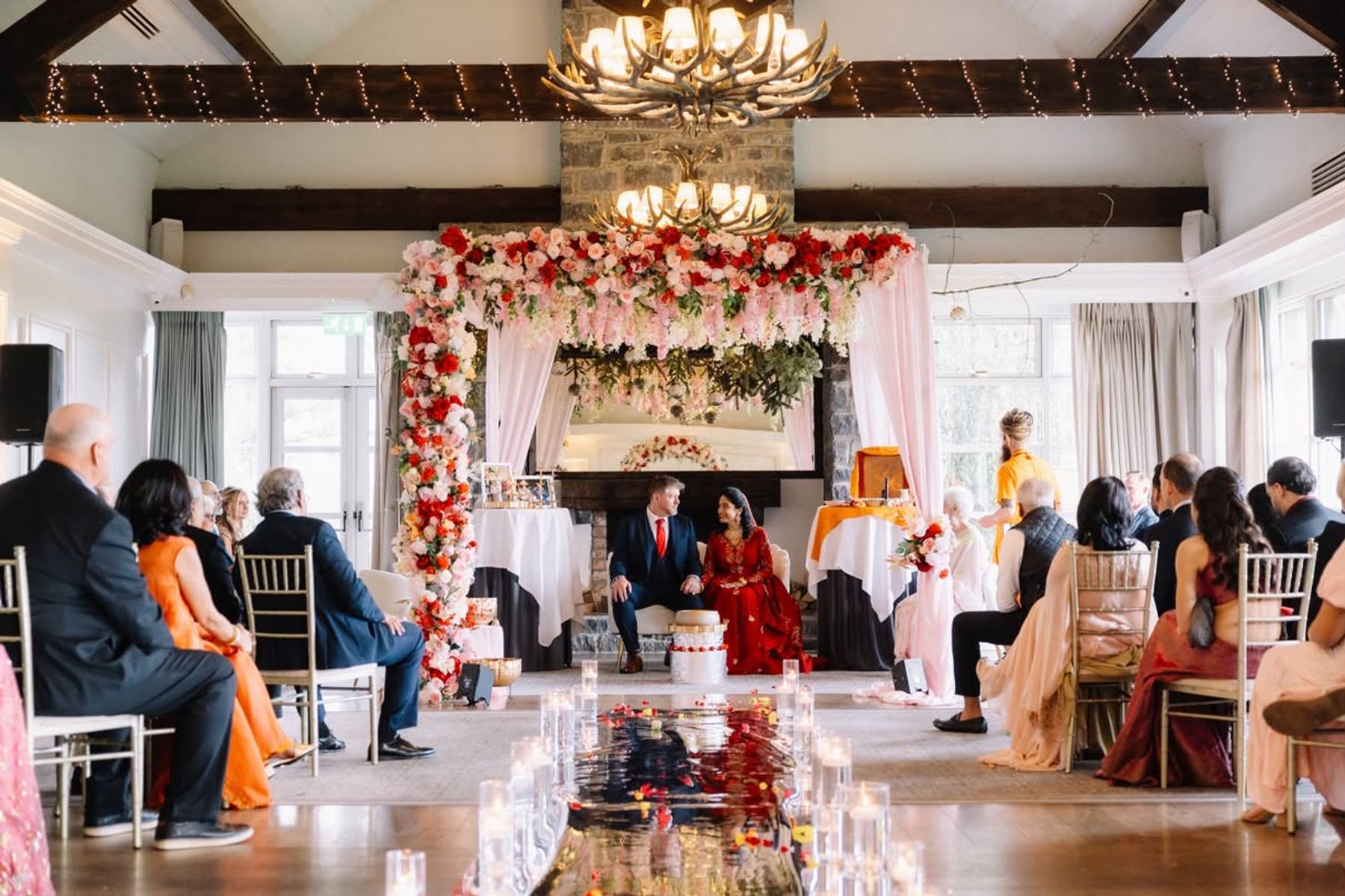A richly coloured ceremonial wedding stage with floral styling and gold seating
