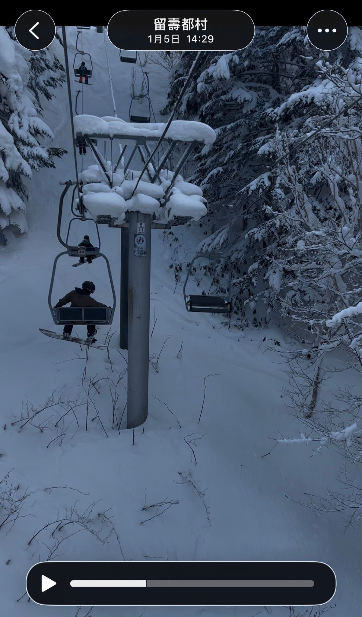 A Rusutsu chairlift running through snow-laden conifers with a lone snowboarder riding up. The capture stamp reads Rusutsu, 5 January, 14:29