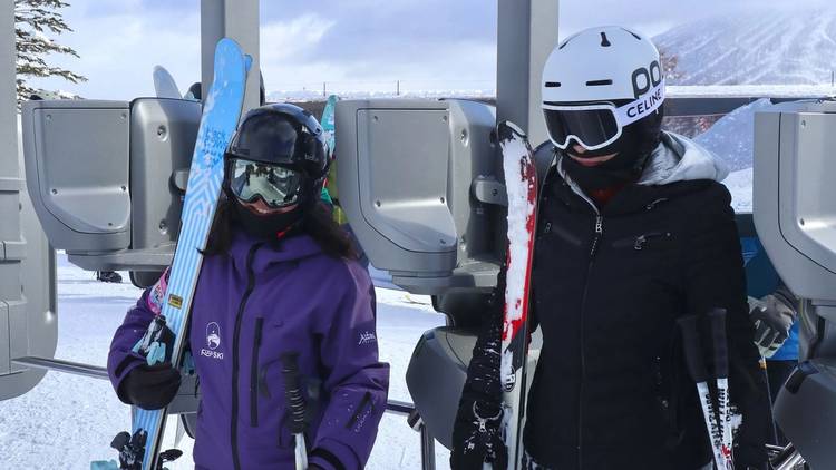 穿 FUYU 紫色制服的教練和學員扛著雪板走出纜車閘口